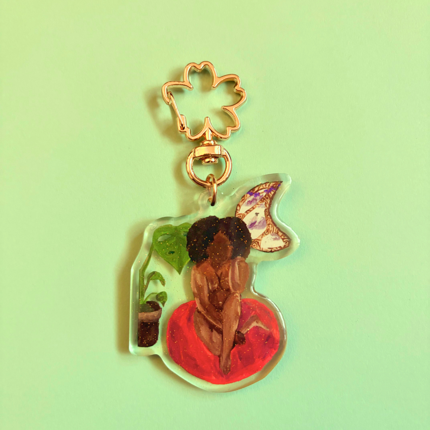 Decorative keychain with a person in a room with a plant and moon window