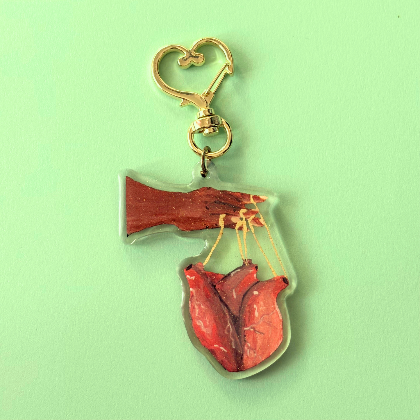 Keychain of hand controlling a heart with puppet strings