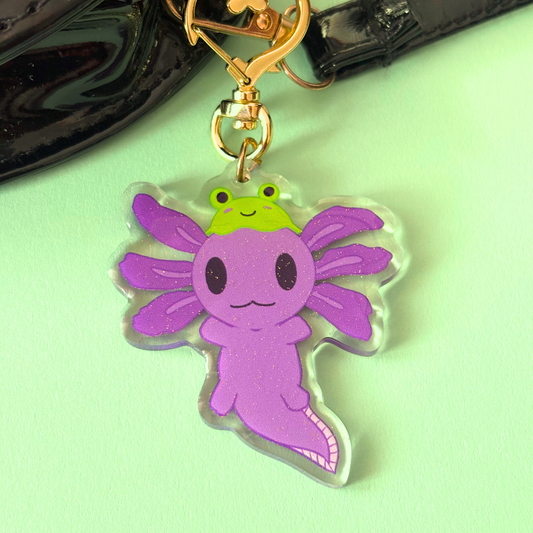 Purple axolotl keychain with a green frog hat