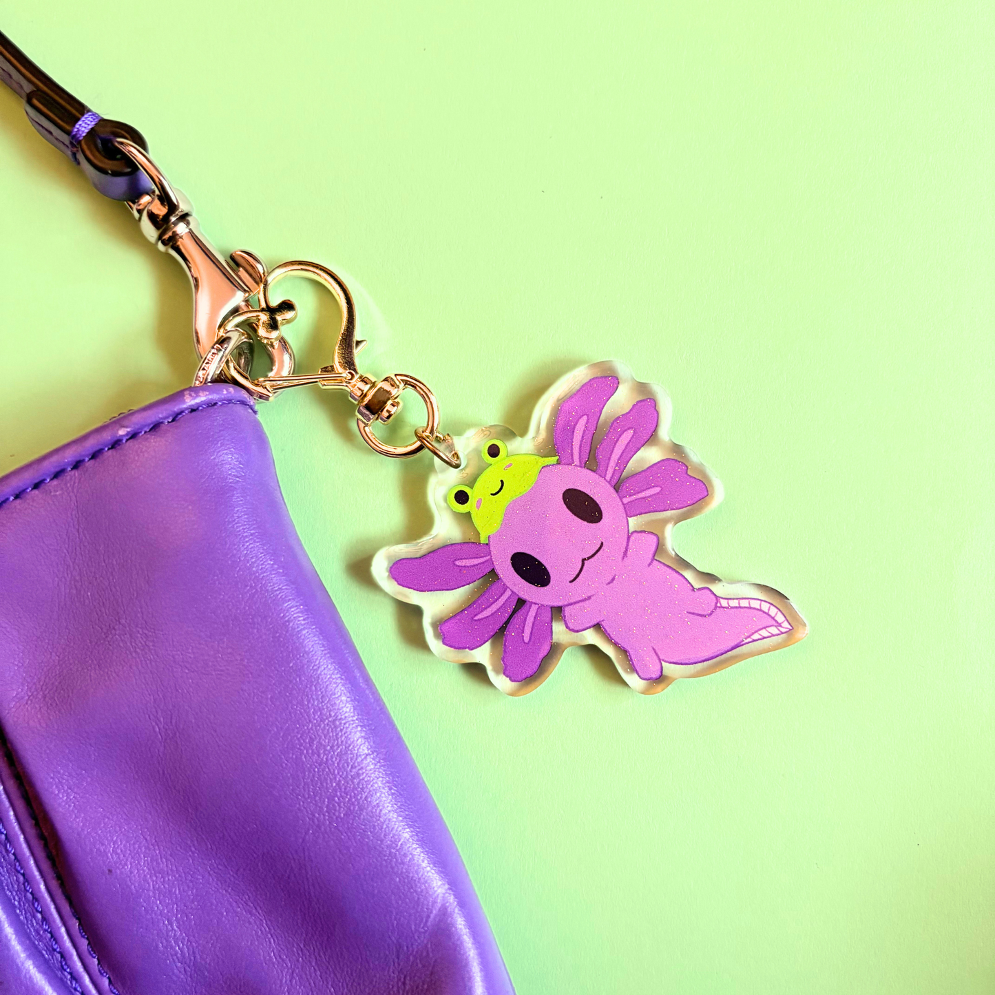 Purple axolotl keychain with a green frog hat