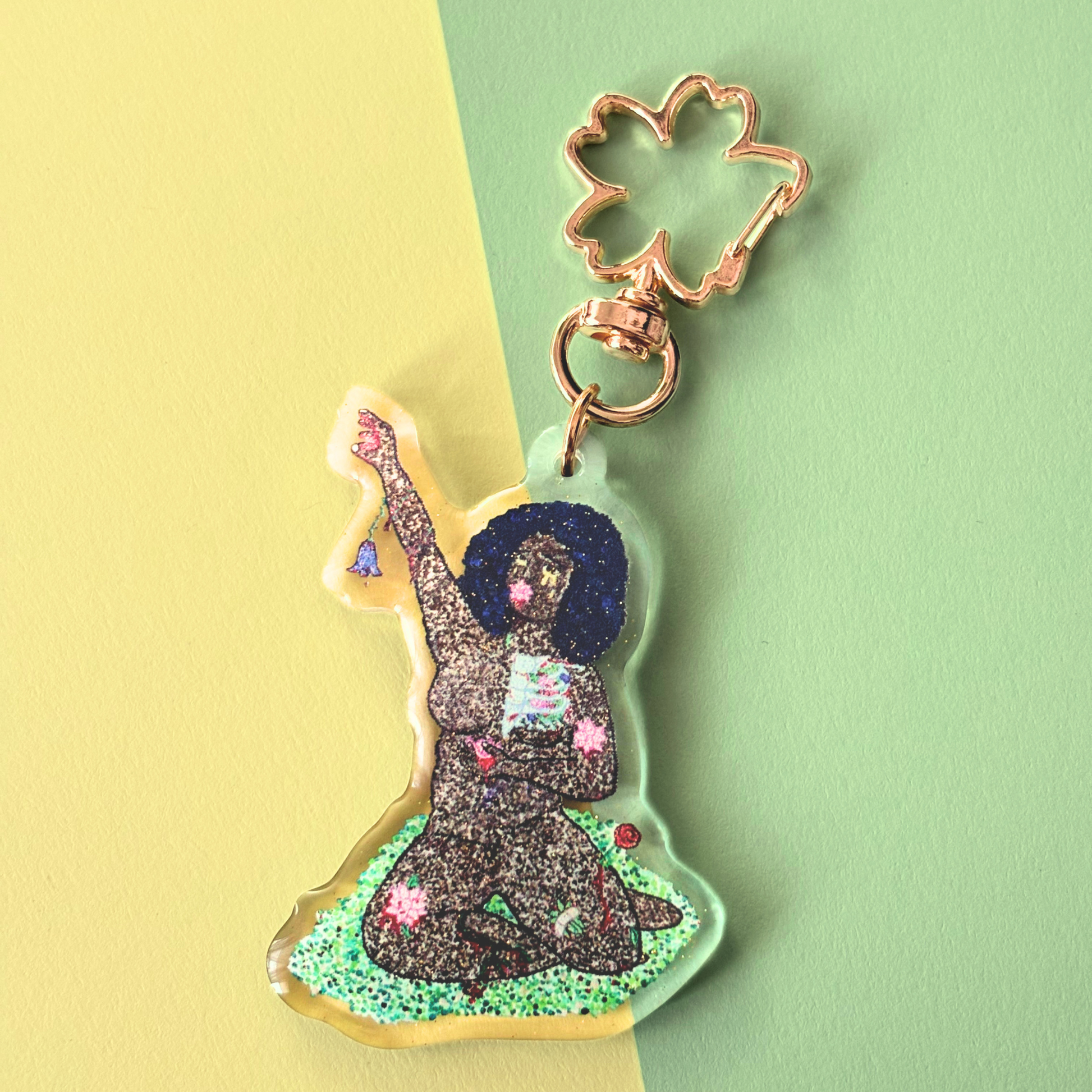 Keychain of woman reaching up with flowers growing from her body.