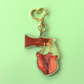 Keychain of hand controlling a heart with puppet strings